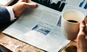 A man reading the paper with a cup of coffee