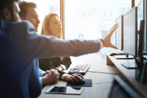 Three colleagues viewing something on a computer screen