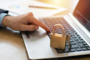 man's hand using laptop with padlock on top of it