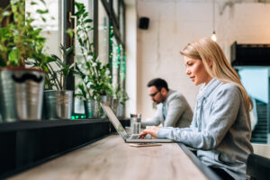 blonde woman using laptop in cafe