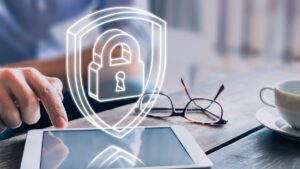 hands using tablet on desk with floating padlock icon