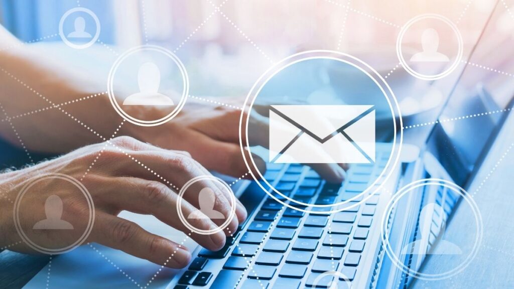 hands typing on a laptop with email and user icons hovering above