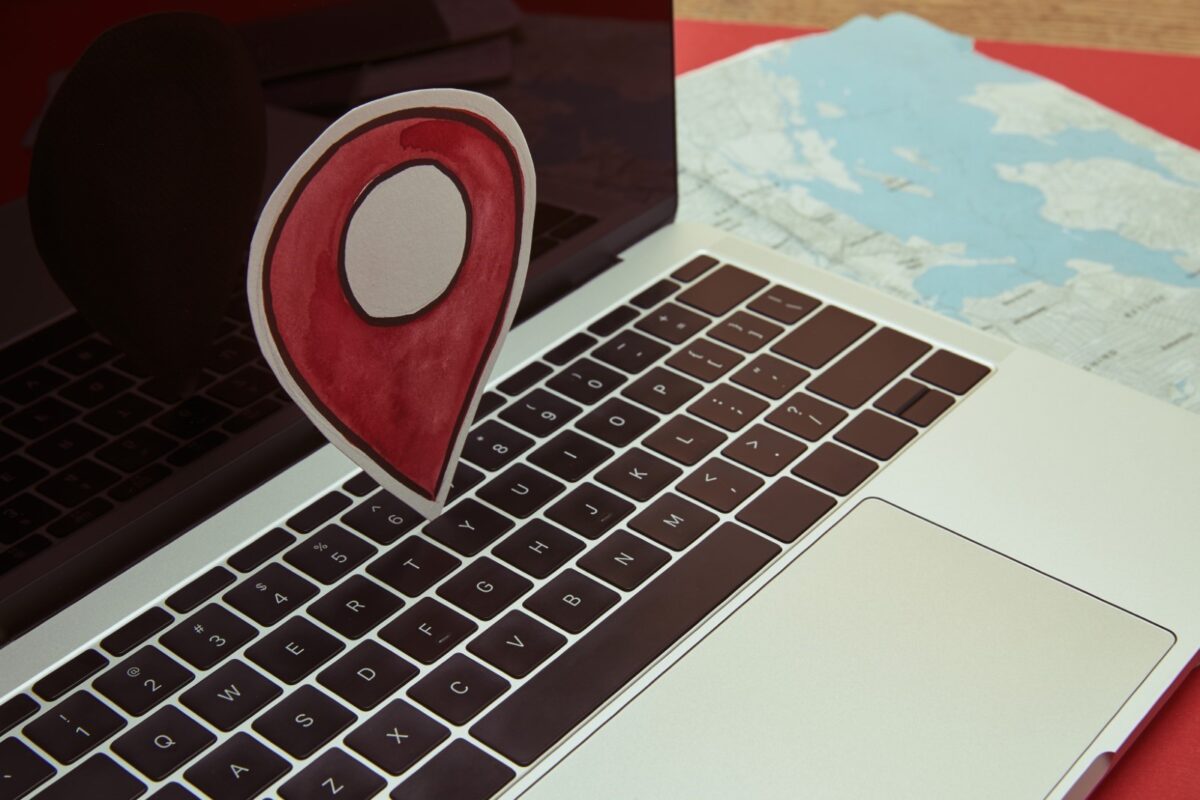 a macbook with the paper cut-out of a map pin on top of the keyboard