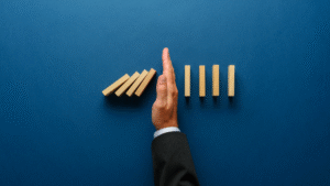 hand blocking a row of dominoes from falling