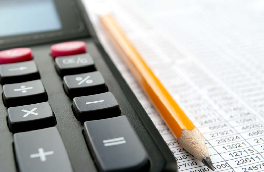 calculator and pencil on top of printed spreadsheet of numbers