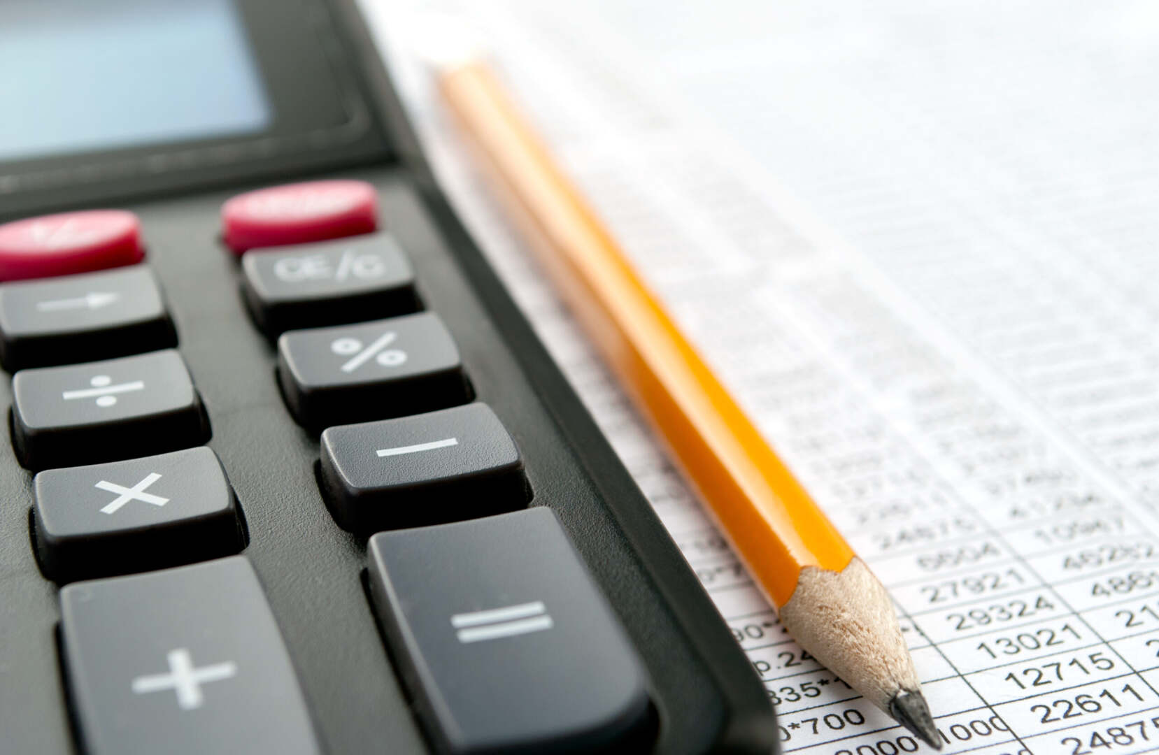 calculator and pencil on top of printed spreadsheet of numbers